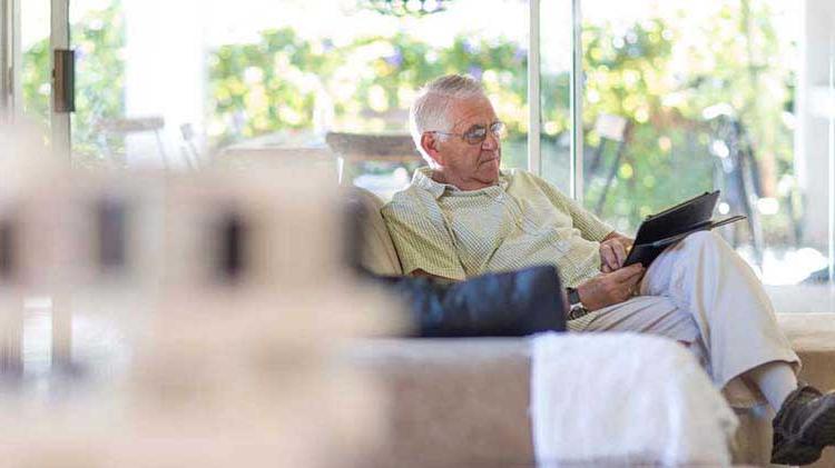 An elderly man on his couch researching Medicare online.