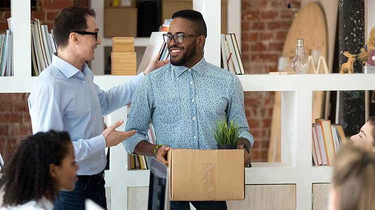 站在办公室里，一个男人拿着一个盒子和另一个男人谈论他的401(k)计划.