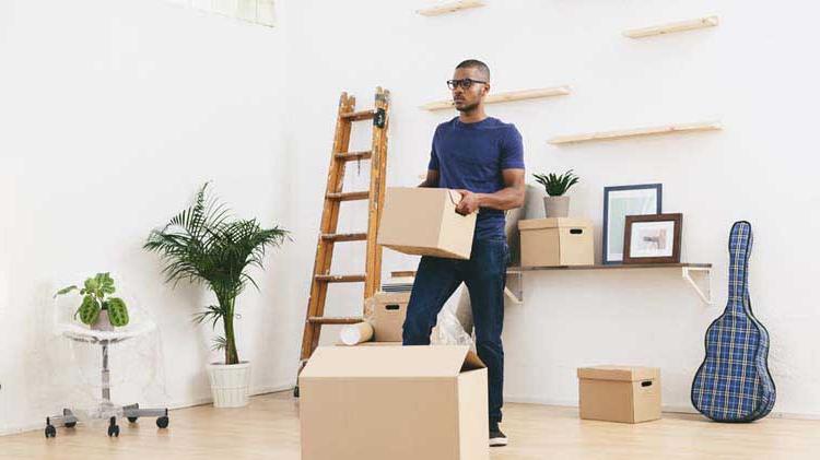 一个人拿着一个盒子，思考着他需要做什么来为一天的搬家做好准备.